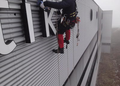 Leuchtwerbung montieren, Arbeit am hängenden Seil