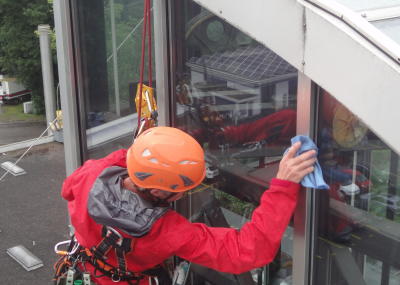 Fassadenkletterer reinigt Glasfront am hängenden Seil, Arbeit am Seil