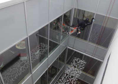 Industriekletterer bei Glasreinigung am hängenden Seil, in Lichtschacht