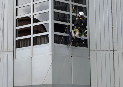 Industriekletterer bei Glasreinigung am hängenden Seil, Arbeit am Seil in der Höhe