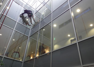 Industriekletterer bei Glasreinigung am hängenden Seil, Arbeit am Seil in Lichtschacht